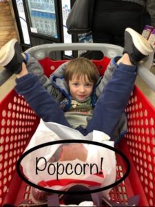 child in shopping trolley with popcorn