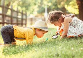 Little boy and girl looking at plants with a magnifying glass